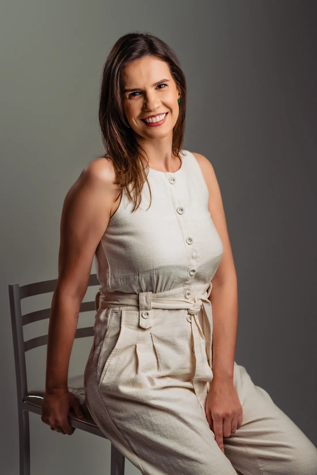 Dra. Mariana Moreira sentada, de roupa clara, em estúdio